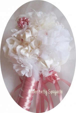Bouquet Shabby Chic com rosas e peónias em cetim tom rosa velho, com apliques de bijuteria e plumas brancas. Pé forrado a cetim e renda branca com aplique prateado com pérola